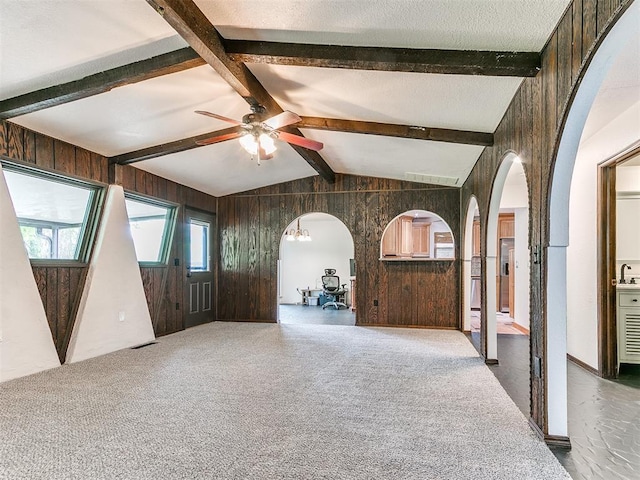 10109 Bison Cir, Yukon, OK 73099 - unfurnished living room featuring wooden walls, arched walkways, a ceiling fan, a sink, and carpet flooring
