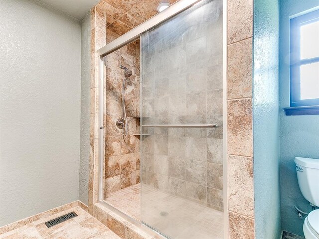 10109 Bison Cir, Yukon, OK 73099 - full bathroom featuring toilet, a stall shower, healthy amount of natural light, a textured wall, and baseboards