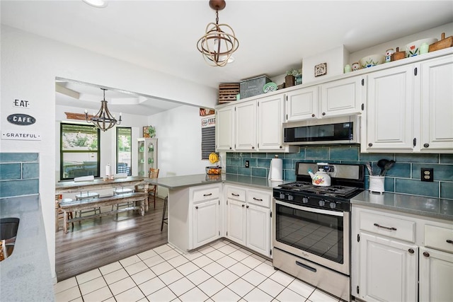 11110 Jeffords Ave, Choctaw, OK 73020 - kitchen with stainless steel appliances, a chandelier, a peninsula, and white cabinetry