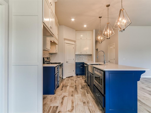 3909 Palisade Ln, Oklahoma City, OK 73179 - kitchen featuring blue cabinets, stainless steel appliances, a chandelier, decorative backsplash, and light countertops