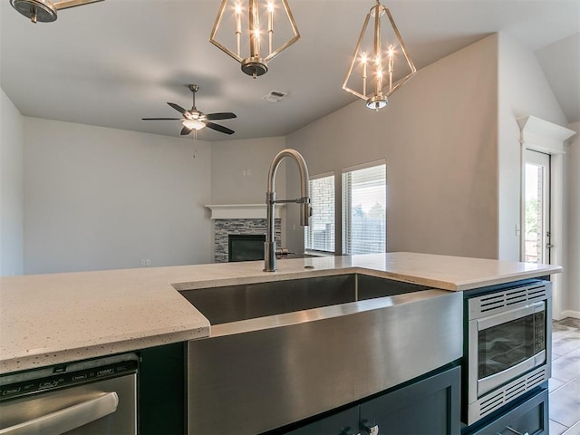 3909 Palisade Ln, Oklahoma City, OK 73179 - kitchen with a sink, appliances with stainless steel finishes, a stone fireplace, light stone counters, and decorative light fixtures