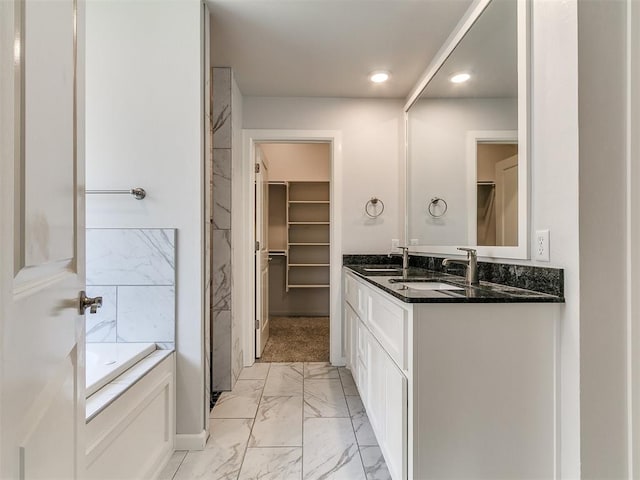 3909 Palisade Ln, Oklahoma City, OK 73179 - bathroom featuring marble look tiles, double vanity, a spacious closet, a garden tub, and recessed lighting