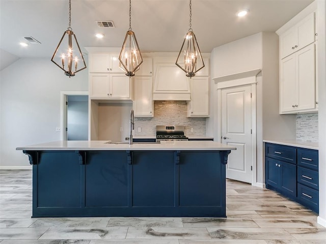 3909 Palisade Ln, Oklahoma City, OK 73179 - kitchen featuring stainless steel range, blue cabinetry, light countertops, tasteful backsplash, and a kitchen bar