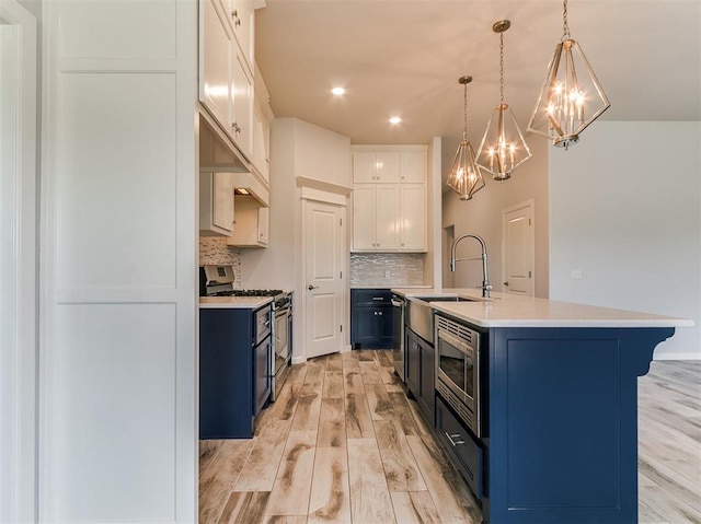 3909 Palisade Ln, Oklahoma City, OK 73179 - kitchen featuring appliances with stainless steel finishes, blue cabinetry, a chandelier, light countertops, and decorative backsplash