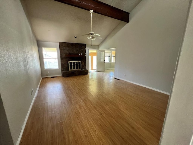 74 Fox Run Cir, Jenks, OK 74037 - unfurnished living room featuring ceiling fan, plenty of natural light, wood finished floors, a stone fireplace, and a textured ceiling