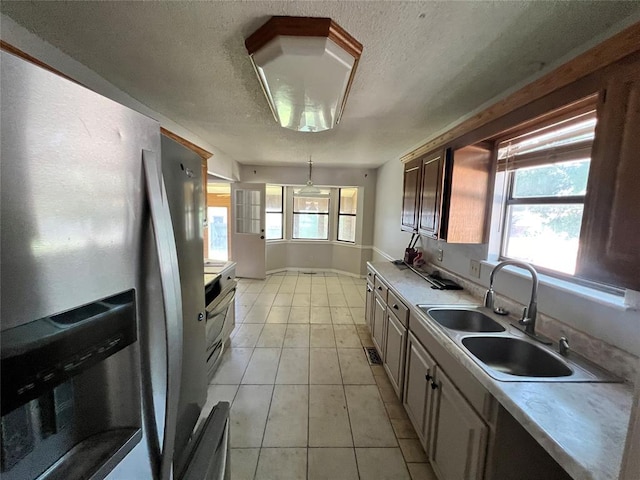 74 Fox Run Cir, Jenks, OK 74037 - kitchen featuring stainless steel refrigerator with ice dispenser, a sink, a textured ceiling, light countertops, and light tile patterned floors