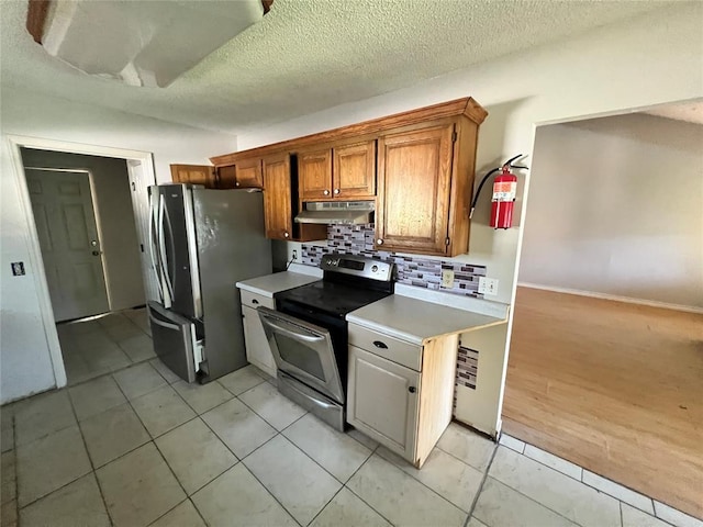 74 Fox Run Cir, Jenks, OK 74037 - kitchen with stainless steel appliances, under cabinet range hood, light countertops, backsplash, and light tile patterned floors