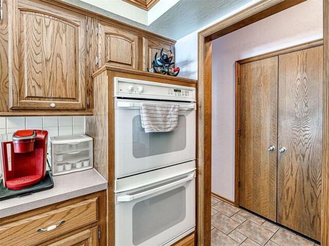 7705 Dripping Springs Ln, Oklahoma City, OK 73150 - kitchen with white double oven, light tile patterned floors, brown cabinetry, and light countertops