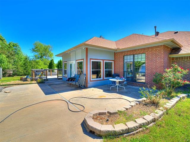 7705 Dripping Springs Ln, Oklahoma City, OK 73150 - back of house featuring a patio, roof with shingles, and brick siding