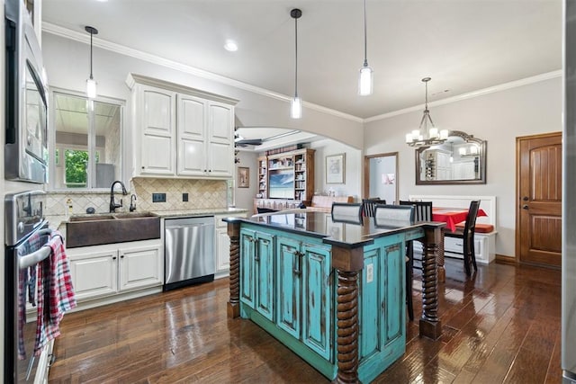 2528 E Bradley St, Shawnee, OK 74804 - kitchen with appliances with stainless steel finishes, a sink, white cabinets, backsplash, and a chandelier