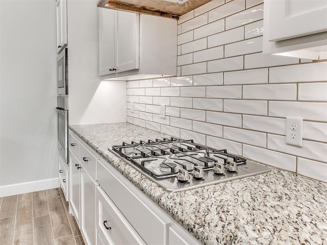 404 Braxton Way, Yukon, OK 73099 - kitchen with stainless steel appliances, baseboards, tasteful backsplash, white cabinets, and light stone counters