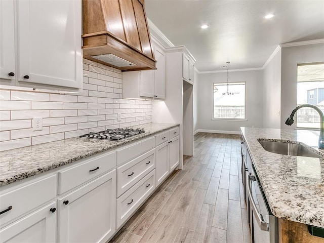 404 Braxton Way, Yukon, OK 73099 - kitchen featuring a sink, premium range hood, crown molding, stainless steel gas stovetop, and light wood-style floors