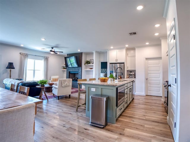 11611 Carefree Ln, Shawnee, OK 74804 - kitchen with stainless steel appliances, open floor plan, recessed lighting, white cabinets, and a brick fireplace