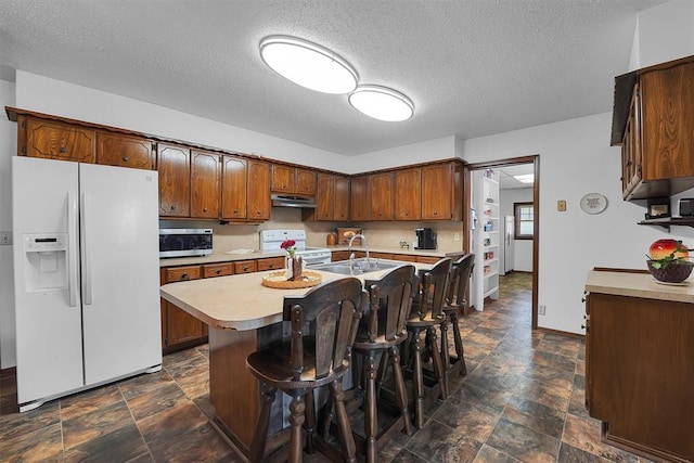 409 S Mcdonald St, Dill City, OK 73641 - kitchen featuring white appliances, a sink, stone finish flooring, under cabinet range hood, and light countertops