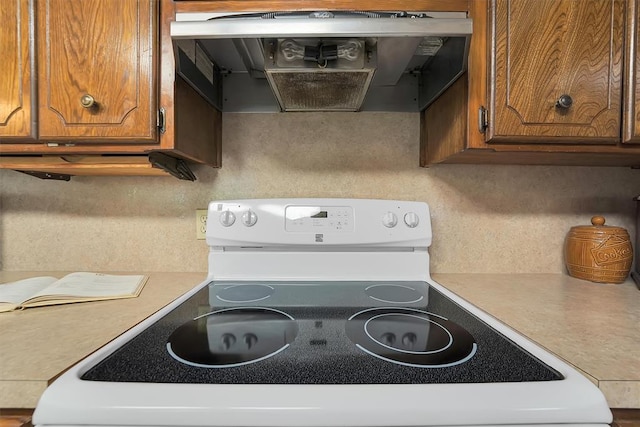 409 S Mcdonald St, Dill City, OK 73641 - kitchen with electric range, ventilation hood, brown cabinets, and light countertops