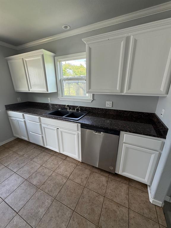 1707 N Louisa Ave, Shawnee, OK 74804 - kitchen featuring stainless steel dishwasher, a sink, white cabinetry, crown molding, and light tile patterned flooring