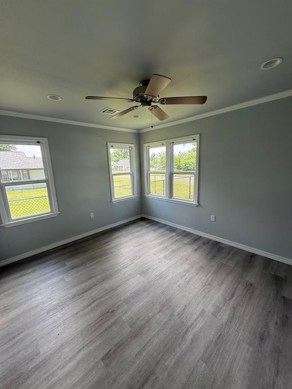 1707 N Louisa Ave, Shawnee, OK 74804 - empty room featuring crown molding, baseboards, dark wood finished floors, and a ceiling fan
