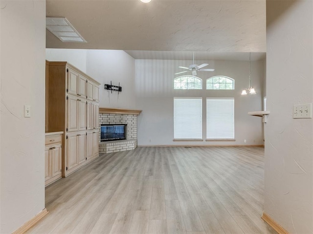 1312 Every Dr, Edmond, OK 73034 - unfurnished living room with ceiling fan, light wood-style floors, a fireplace, baseboards, and a chandelier