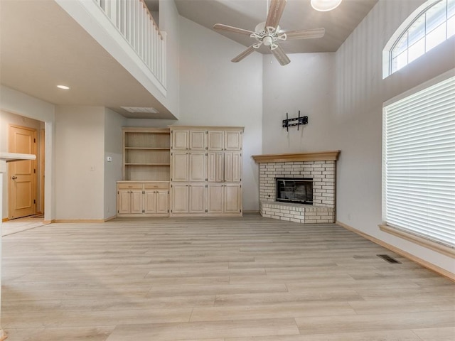 1312 Every Dr, Edmond, OK 73034 - unfurnished living room with a towering ceiling, baseboards, a ceiling fan, a fireplace, and light wood-style floors