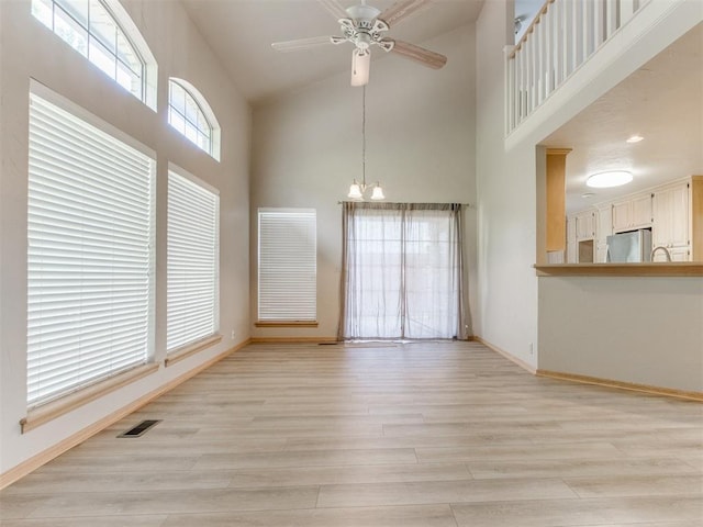 1312 Every Dr, Edmond, OK 73034 - unfurnished dining area featuring high vaulted ceiling, light wood-style flooring, baseboards, ceiling fan, and a chandelier