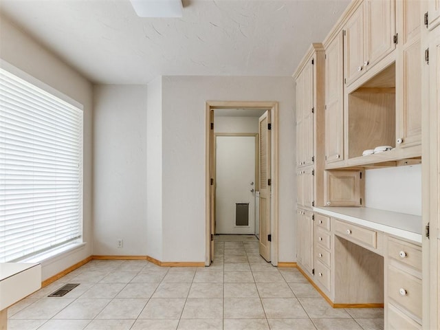 1312 Every Dr, Edmond, OK 73034 - unfurnished office featuring built in desk, healthy amount of natural light, baseboards, and light tile patterned floors