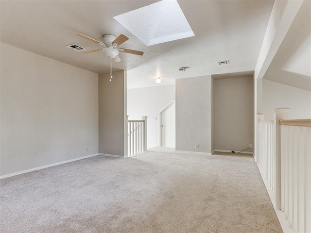 1312 Every Dr, Edmond, OK 73034 - empty room featuring ceiling fan, light colored carpet, and a skylight