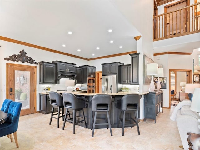 205 W Waterfront Dr, Tuttle, OK 73089 - kitchen featuring appliances with stainless steel finishes, light countertops, a peninsula, a kitchen bar, and ornamental molding