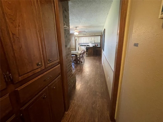 139 Sheridan Pl, Chickasha, OK 73018 - hall featuring a textured ceiling, dark wood-style floors, and a textured wall