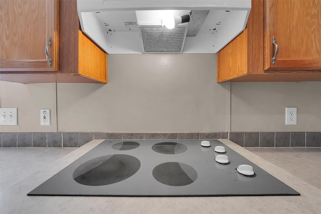 1318 N Cook St, Cordell, OK 73632 - kitchen view of electric stovetop, exhaust hood, brown cabinetry, and light countertops