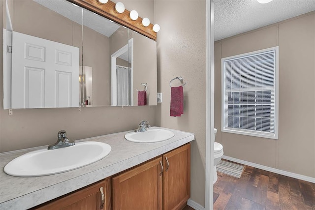 1318 N Cook St, Cordell, OK 73632 - bathroom with a textured ceiling, wood finished floors, double vanity, and toilet