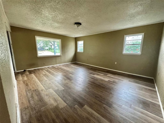 1502 S 12th St, Chickasha, OK 73018 - empty room featuring wood finished floors, a textured ceiling, baseboards, and a textured wall