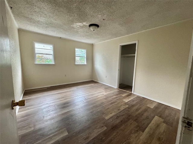 1502 S 12th St, Chickasha, OK 73018 - unfurnished bedroom with a textured wall, a textured ceiling, wood finished floors, baseboards, and a closet