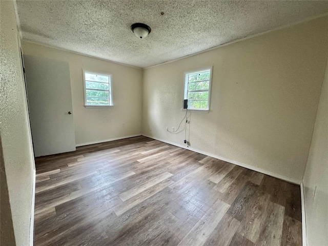 1502 S 12th St, Chickasha, OK 73018 - empty room with healthy amount of natural light, wood finished floors, a textured ceiling, a textured wall, and baseboards