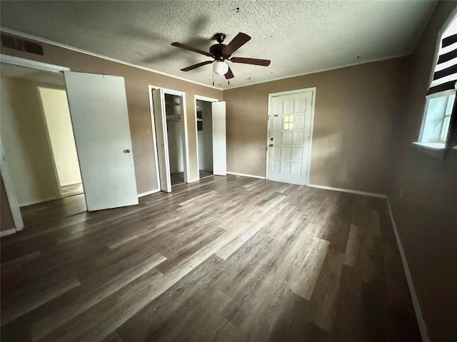 1502 S 12th St, Chickasha, OK 73018 - unfurnished bedroom with a textured ceiling, wood finished floors, baseboards, multiple closets, and ceiling fan