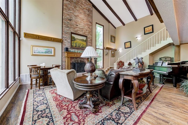 1736 Bryant Cir, Norman, OK 73026 - living area with high vaulted ceiling, stairs, a fireplace, wood finished floors, and beam ceiling