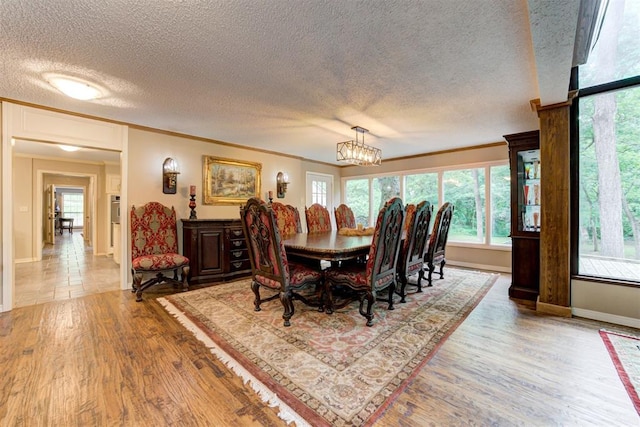 1736 Bryant Cir, Norman, OK 73026 - dining area with a textured ceiling, wood finished floors, crown molding, baseboards, and a chandelier
