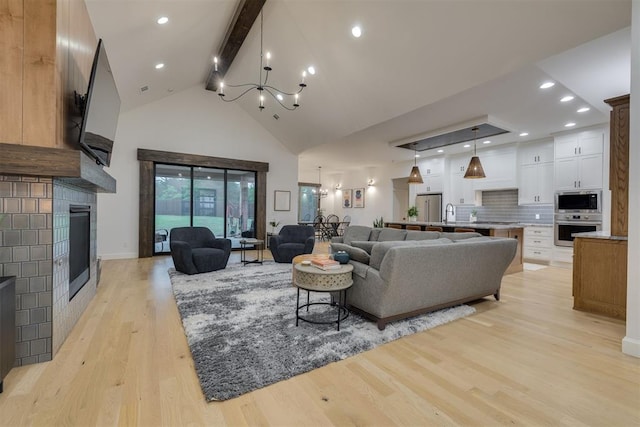 6524 NE 96th Cir, Oklahoma City, OK 73151 - living area featuring a chandelier, beamed ceiling, light wood-type flooring, high vaulted ceiling, and a glass covered fireplace