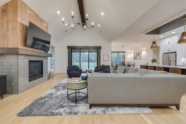6524 NE 96th Cir, Oklahoma City, OK 73151 - living room featuring light wood finished floors, a chandelier, beamed ceiling, high vaulted ceiling, and a glass covered fireplace