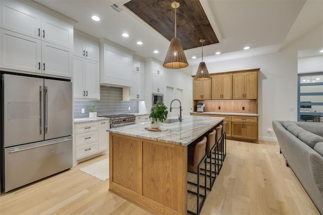 6524 NE 96th Cir, Oklahoma City, OK 73151 - kitchen featuring high quality appliances, light wood-type flooring, tasteful backsplash, recessed lighting, and a kitchen breakfast bar