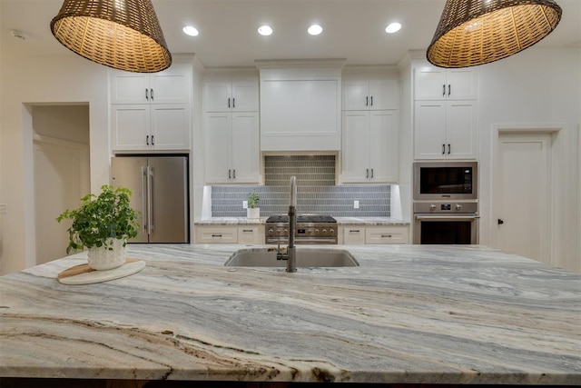 6524 NE 96th Cir, Oklahoma City, OK 73151 - kitchen featuring appliances with stainless steel finishes, a spacious island, tasteful backsplash, white cabinetry, and light stone countertops