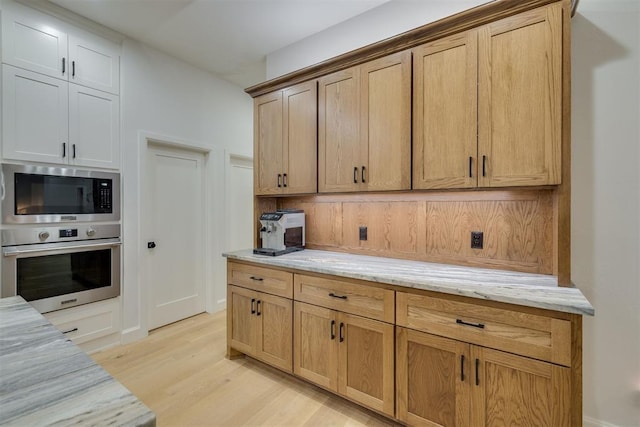 6524 NE 96th Cir, Oklahoma City, OK 73151 - kitchen with appliances with stainless steel finishes, light wood-style floors, and light stone countertops