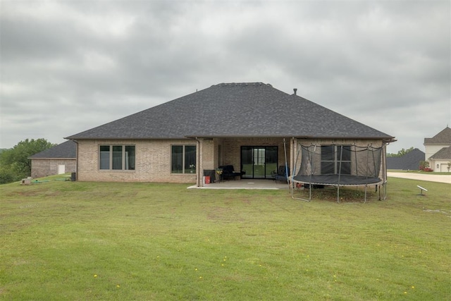6524 NE 96th Cir, Oklahoma City, OK 73151 - rear view of house with a trampoline, a patio, a lawn, brick siding, and roof with shingles