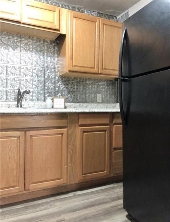 16204 Gaddy Rd, Shawnee, OK 74801 - kitchen featuring freestanding refrigerator, backsplash, light wood-style flooring, light stone counters, and a sink