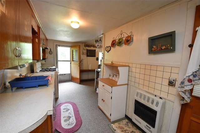 220 E Tiger Ave, Wetumka, OK 74883 - kitchen with heating unit, white range with gas stovetop, light countertops, white cabinets, and a wall unit AC