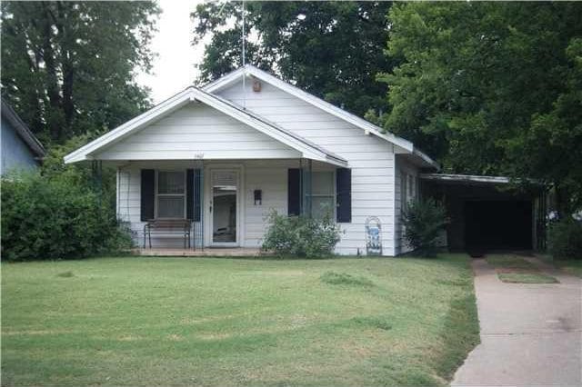 1407 S 9th St, Chickasha, OK 73018 - bungalow-style house featuring a porch, a front lawn, and driveway