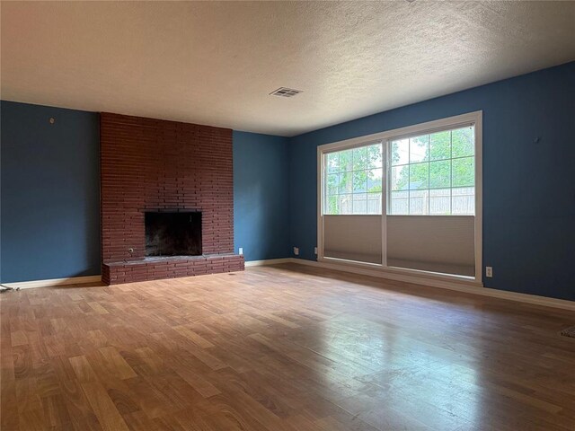 2125 Fremont Dr, The Village, OK 73120 - unfurnished living room featuring wood finished floors, a brick fireplace, baseboards, and a textured ceiling