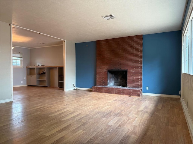 2125 Fremont Dr, The Village, OK 73120 - unfurnished living room featuring wood finished floors, baseboards, a brick fireplace, and a textured ceiling
