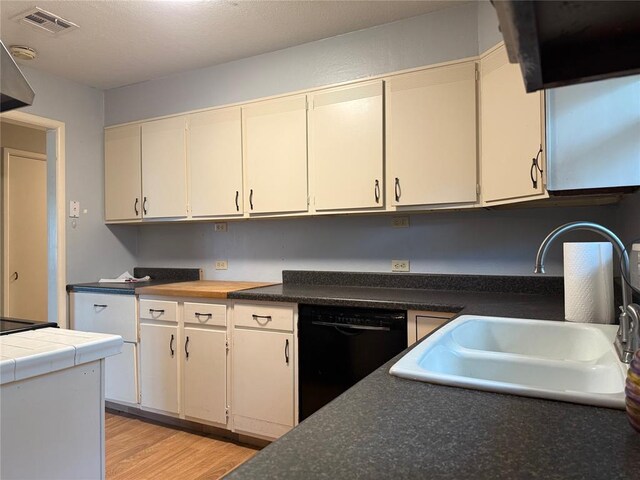2125 Fremont Dr, The Village, OK 73120 - kitchen with dishwasher, a sink, light wood-style flooring, and dark countertops