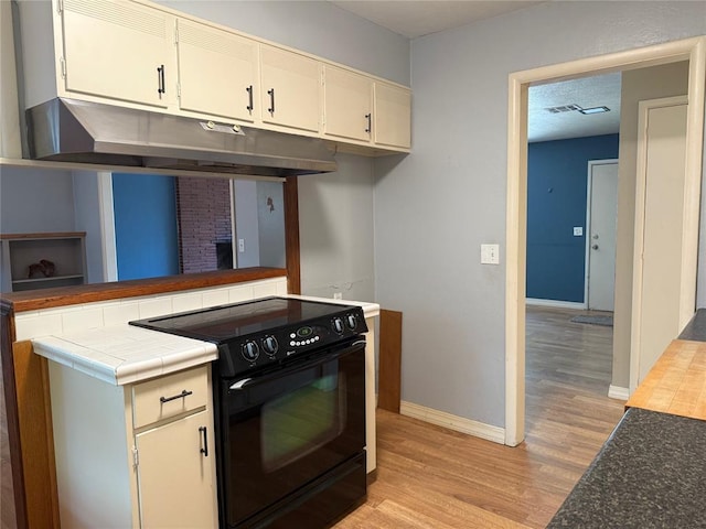 2125 Fremont Dr, The Village, OK 73120 - kitchen with black electric range, light wood-style flooring, baseboards, and under cabinet range hood