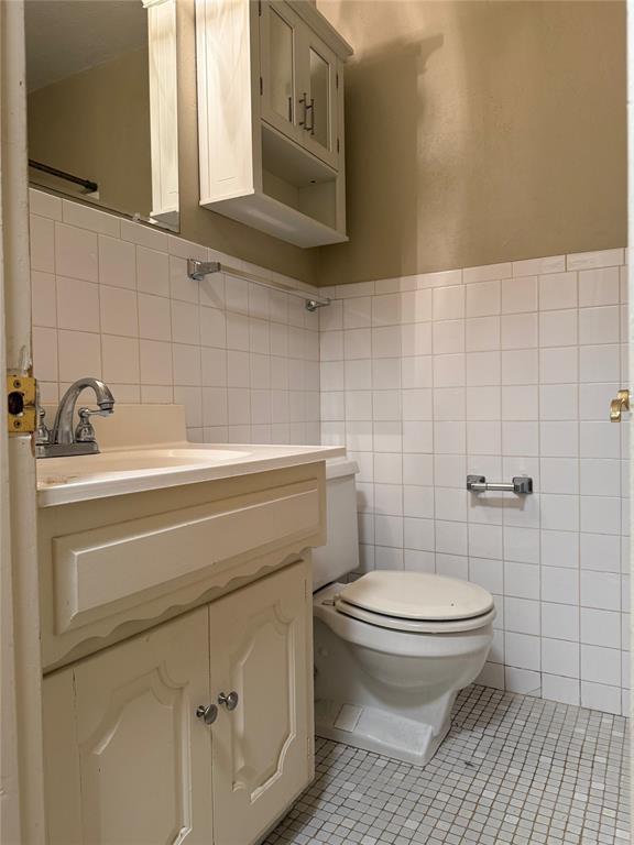 2125 Fremont Dr, The Village, OK 73120 - bathroom with tile walls, tile patterned flooring, toilet, and vanity